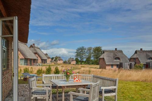 a table and chairs on a patio in a village at Reetdorf Geltinger Birk Künstlerkate Eisvogel in Nieby
