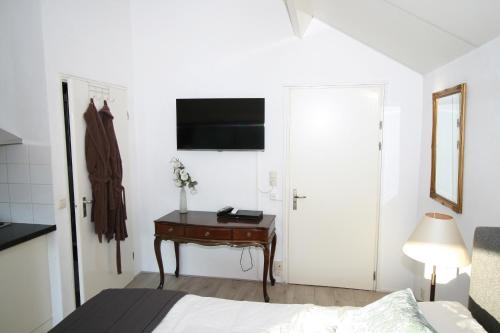 a bedroom with a bed and a desk with a television at Villa 't Haasduin in Wijk aan Zee