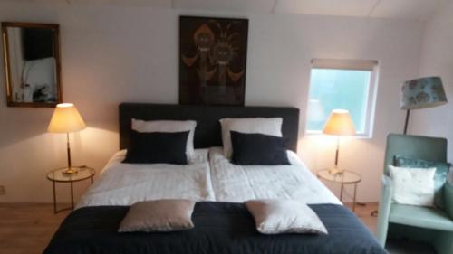a bedroom with a large bed with two lamps and a chair at Villa 't Haasduin in Wijk aan Zee