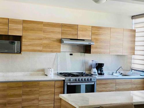 uma cozinha com armários de madeira e um forno com placa de fogão em Amplia casa cerca de zona industrial em San Luis Potosí