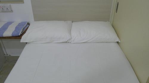 1 cama con 2 almohadas blancas en una habitación en Ruby Star Hostel Dubai G P-34567 en Dubái