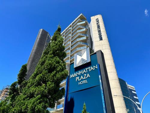 un edificio con un cartel delante de un árbol en Manhattan Plaza, en Brasilia