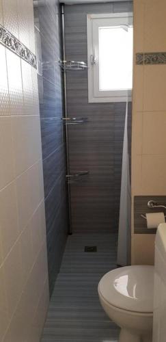 ein Bad mit Dusche, WC und Fenster in der Unterkunft Algo2 in Salamís