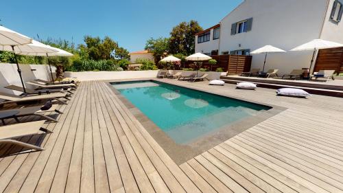 a swimming pool with chairs and umbrellas on a wooden deck at Résidence Villa Branda in Calvi