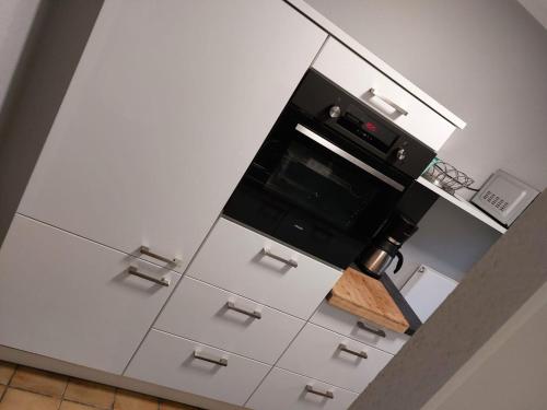 eine Küche mit weißen Schubladen und einem schwarzen Backofen in der Unterkunft JoPit Haus in Baesweiler