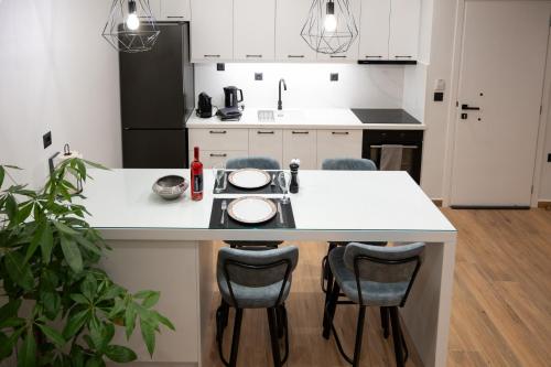 una cocina con una isla blanca con sillas en Kefaloviso Luxury Apartment 2, en Nafpaktos
