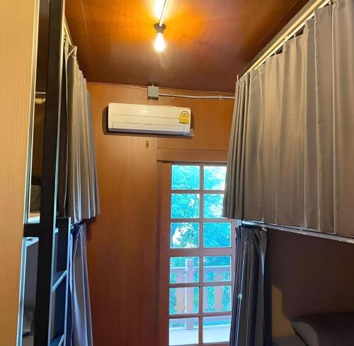 una camera con finestra e condizionatore d'aria di Cozy Hub Hostel a Chiang Mai