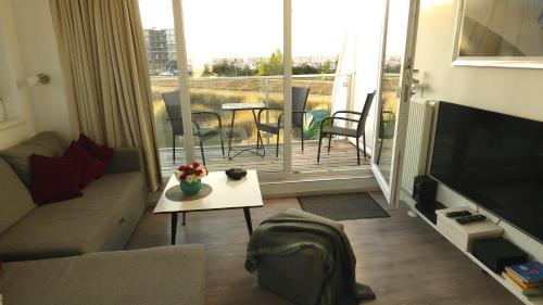 a living room with a couch and a table and a balcony at Ferienhaus Meerzeit Marina Wendtorf in Wendtorf