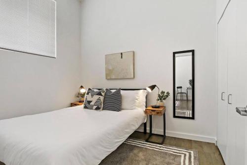 um quarto branco com uma cama e um espelho em 1BR Adorable Apt with In-unit Laundry - Lake 206 em Chicago