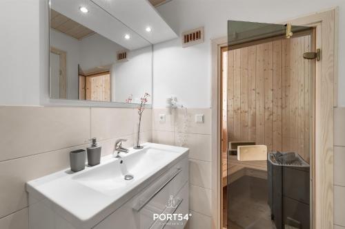 a white bathroom with a sink and a mirror at Ferienhaus Möwennest Marina Wendtorf in Wendtorf