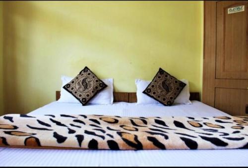 um quarto com uma cama com lençóis brancos e almofadas em Divine blessing em Manali