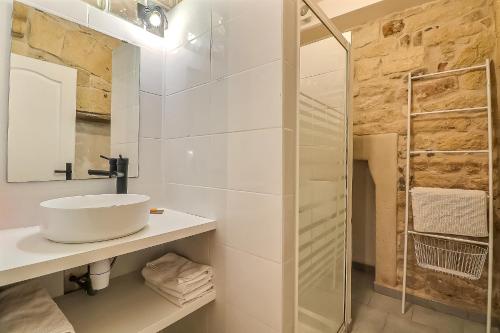 een witte badkamer met een wastafel en een douche bij Hyper Centre Terrasse Wifi La Pierre d'Histoire in Beaucaire