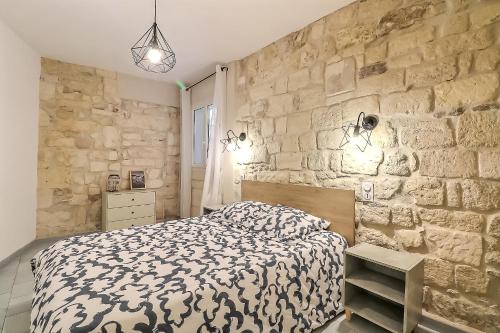 een slaapkamer met een bed en een stenen muur bij Hyper Centre Terrasse Wifi La Pierre d'Histoire in Beaucaire