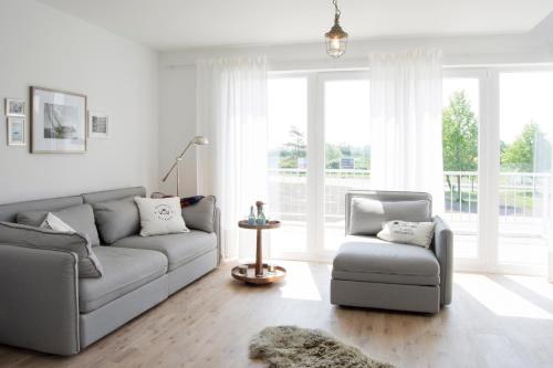 ein Wohnzimmer mit einem Sofa und einem Stuhl in der Unterkunft Oceanhouse in Olpenitz