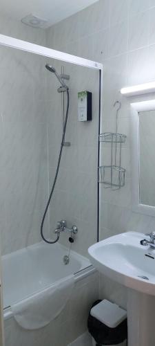 uma casa de banho branca com um lavatório e um chuveiro em Hostal Rosales em Aranda de Duero