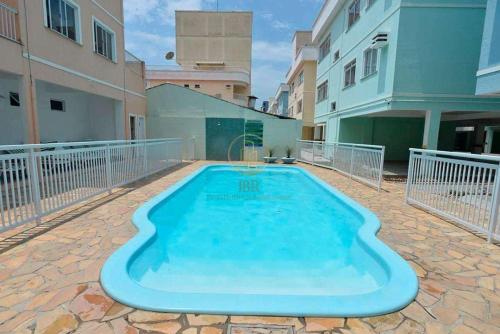 une grande piscine bleue dans la cour d'un bâtiment dans l'établissement Apartamento 17 San Victor, à Bombinhas