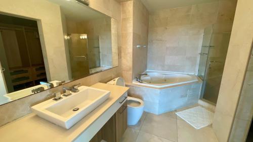 La salle de bains est pourvue d'un lavabo, d'une baignoire et de toilettes. dans l'établissement 10G Perfect 2 Bedroom with Ocean and Jungle Views, à ArraijÃ¡n