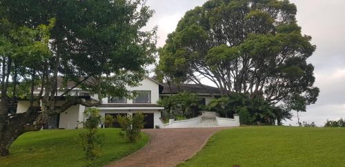 a white house with a green lawn and trees at Paradise View Guesthouse in Graskop