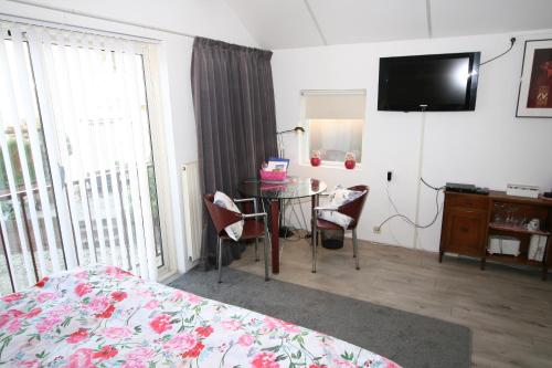 a bedroom with a bed and a table and a television at Villa 't Haasduin in Wijk aan Zee