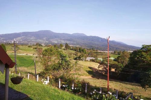 a field with a fence and mountains in the background at La Cabaña in Heredia