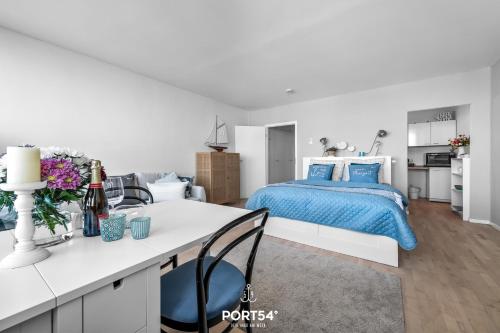 a white bedroom with a blue bed and a kitchen at Waterfront 7601 Marina Wendtorf in Wendtorf