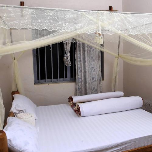 a bedroom with a canopy bed with a window at Sipi Guest House in Kapchorwa