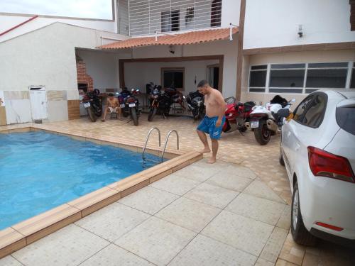 a man standing in front of a swimming pool at Apartamento in Petrolina