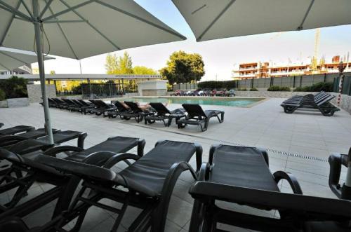 eine Reihe von Stühlen und ein Sonnenschirm neben einem Pool in der Unterkunft Aparthotel Oceano Atlântico 1 in Portimão
