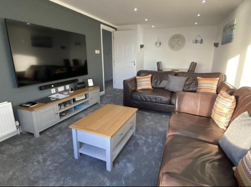 a living room with a couch and a flat screen tv at Prime Dalgety Bay Waterfront Apartment in Saint Davids