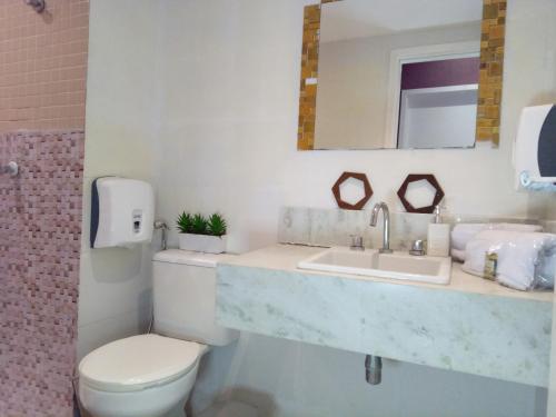 a bathroom with a sink and a toilet and a mirror at Flat Top Barra da tijuca Com SPA in Rio de Janeiro