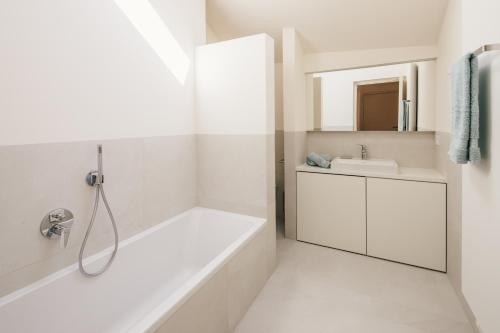 a white bathroom with a tub and a sink at Appartement Steinach in Schenna