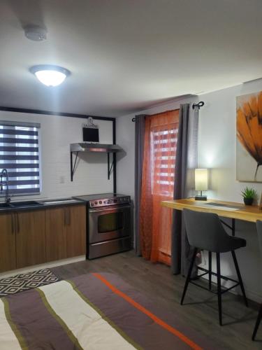 uma cozinha com uma secretária, uma mesa e um fogão em Motel domaine l'Avantage Inn em Roberval