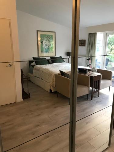 a bedroom with a bed and a table and a mirror at Villa 't Haasduin in Wijk aan Zee