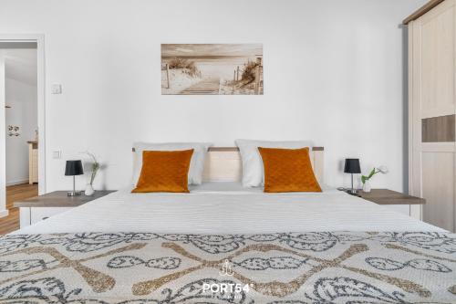 ein Schlafzimmer mit einem großen weißen Bett mit orangefarbenen Kissen in der Unterkunft Ferienwohnung Ostseeinsel Fehmarn in Fehmarn