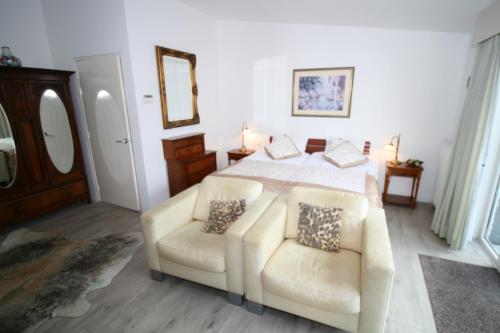 a bedroom with a bed and two chairs at Villa 't Haasduin in Wijk aan Zee
