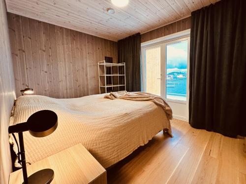 ein Schlafzimmer mit einem Bett und einem großen Fenster in der Unterkunft Superior Ocean View Lofoten in Ballstad