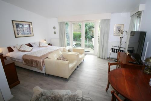 a bedroom with a bed and a couch and a table at Villa 't Haasduin in Wijk aan Zee