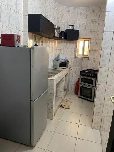 Il comprend une cuisine équipée d'un réfrigérateur blanc et d'une cuisinière. dans l'établissement AGENCE IMMOBILIÈRE GDS BENIN, à Abomey-Calavi