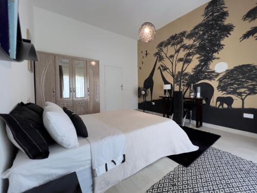 ein Schlafzimmer mit einem großen Bett mit Wandbild in der Unterkunft La Caduta Luxury Villa in Livingstone