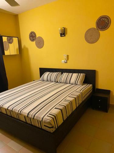 1 dormitorio con 1 cama en una pared amarilla en AGENCE IMMOBILIÈRE GDS BENIN en Abomey-Calavi
