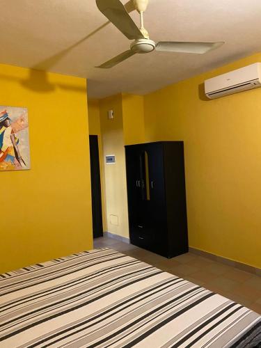 Habitación con paredes amarillas y ventilador de techo. en AGENCE IMMOBILIÈRE GDS BENIN, en Abomey-Calavi