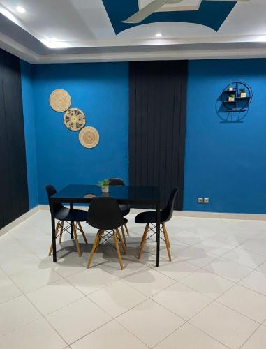 Abomey-Calavi的住宿－AGENCE IMMOBILIÈRE GDS BENIN，一间设有蓝色墙壁和桌椅的用餐室