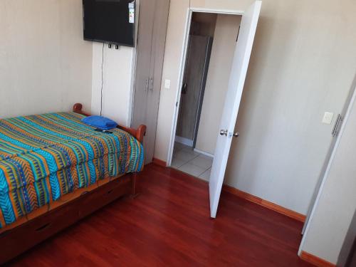 Dormitorio pequeño con cama y TV en Comparto Depto. en La Cisterna ( hermoso y cómodo, cómo en casa) en Santiago