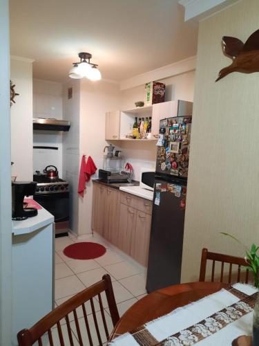 a kitchen with a black refrigerator and a table at Comparto Depto. en La Cisterna ( hermoso y cómodo, cómo en casa) in Santiago