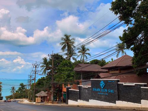a building with a sign on the side of a street at Baan Hin Sai Resort & Spa in Chaweng Noi Beach