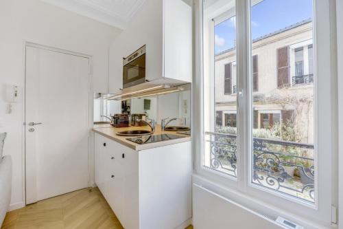 une cuisine blanche avec un évier et une fenêtre dans l'établissement Studio luxe et cosy 2 à 4 personnes Proche de Paris, à Saint-Maurice