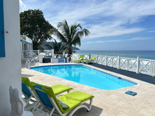 a swimming pool with chairs and the ocean in the background at North Star Villa Oceanfront Family-Retreat With Pool in Frederiksted