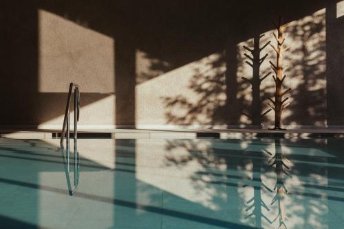 a swimming pool with a reflection of trees in the water at Hotel Lech Da Sompunt in Badia