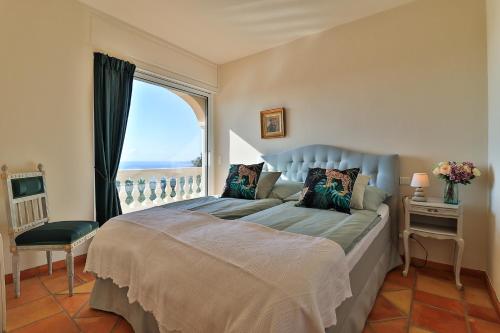 une chambre avec un grand lit avec une grande fenêtre dans l'établissement Luxus Villa Horizon Bleu - mit Meerblick und Infinity Pool by Riviera HomeLife, à Sainte-Maxime