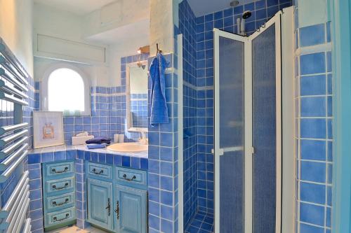 une salle de bain carrelée bleue avec un lavabo et une douche dans l'établissement Luxus Villa Horizon Bleu - mit Meerblick und Infinity Pool by Riviera HomeLife, à Sainte-Maxime
